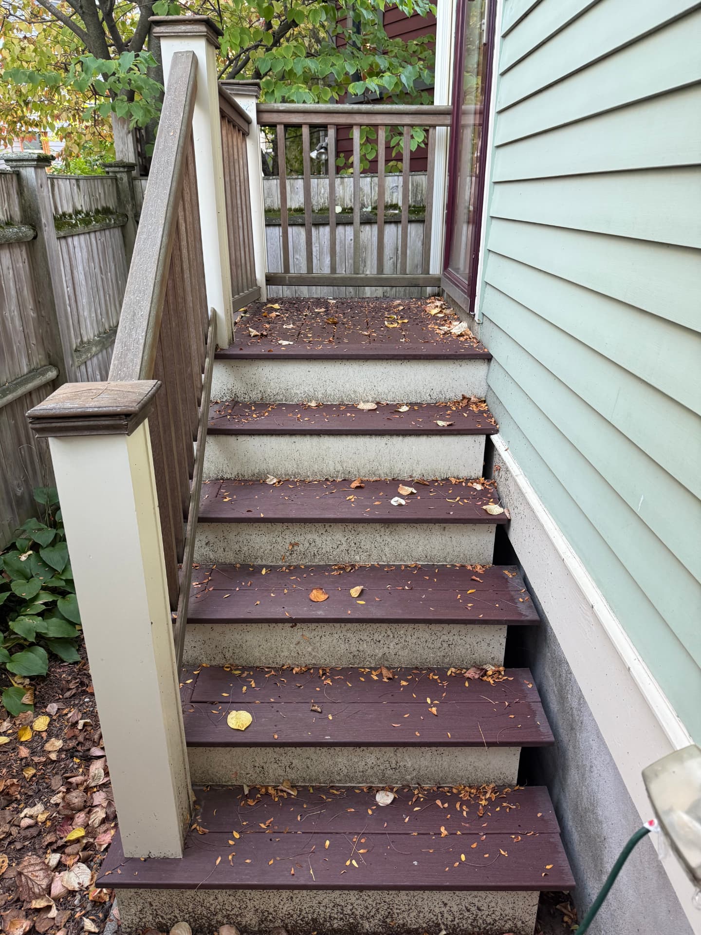 Deck stairs covered in leaves with dirty risers before cleaning