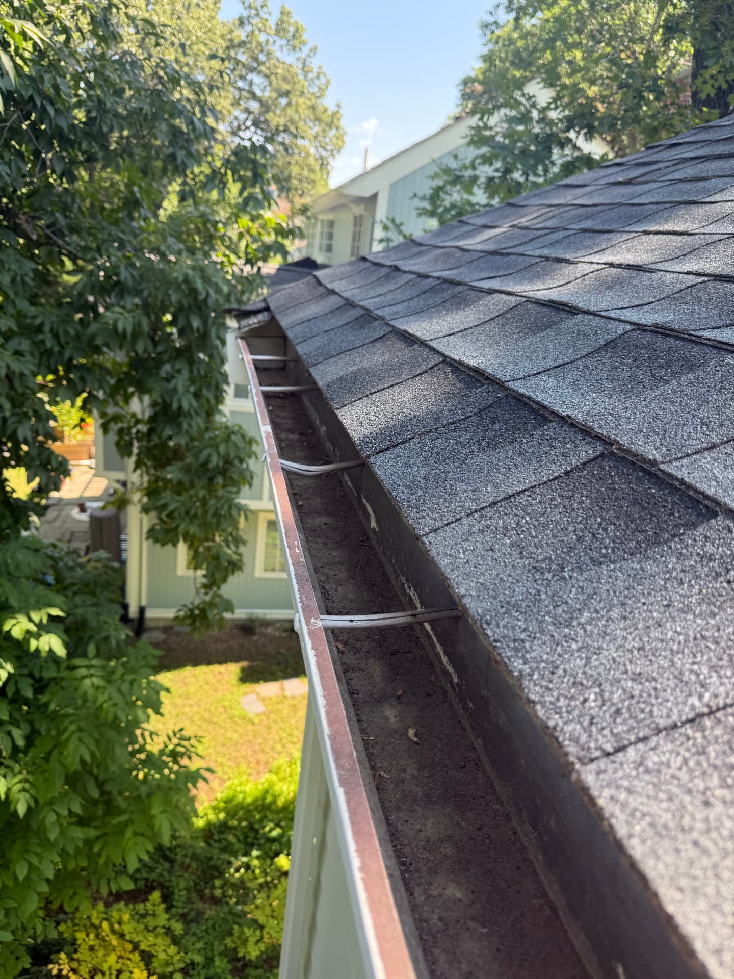 Gutter packed with dark silt before cleaning
