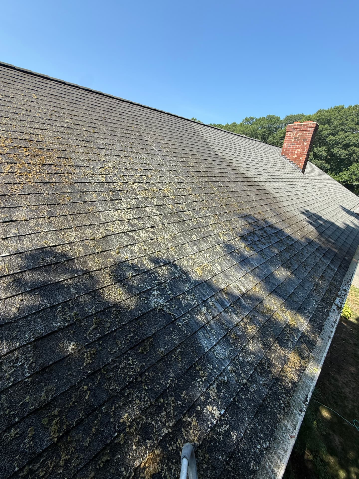 The same roof near the chimney with moss removed after professional treatment