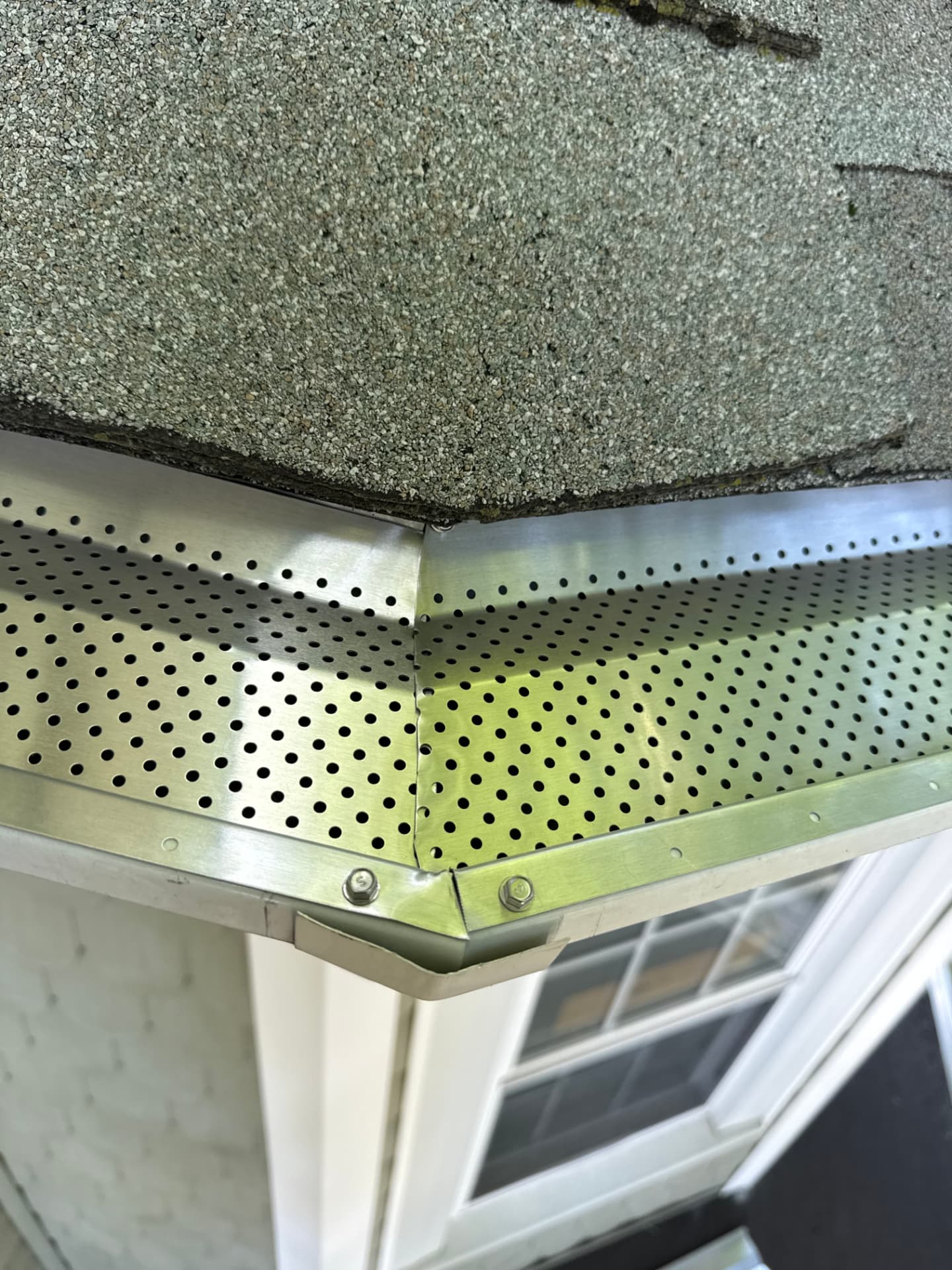 Close-up of a professionally installed perforated metal gutter guard seam